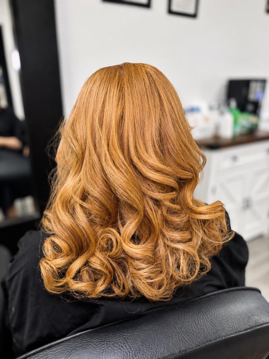 Glossy honey-blonde Dominican blowout with bouncy curls at Yokasta Dominican Hair Salon in Stockbridge, GA
